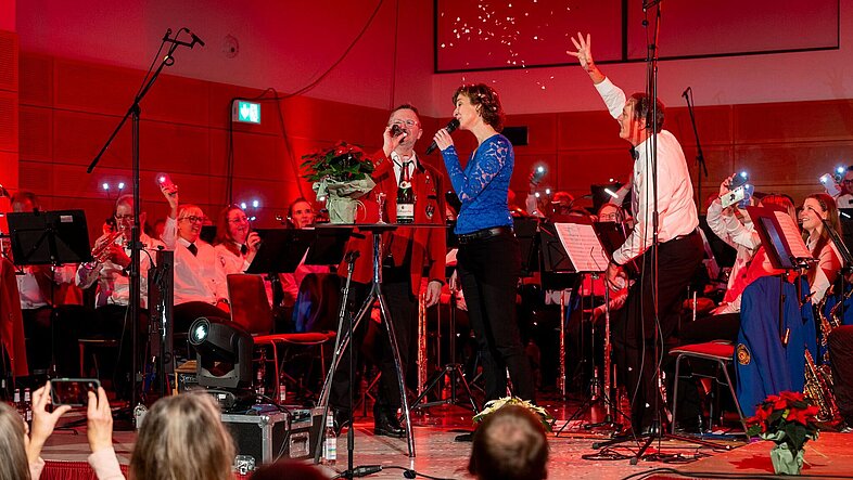 Konzert mit Dirigenten auf der Bühne am Mikrophon 