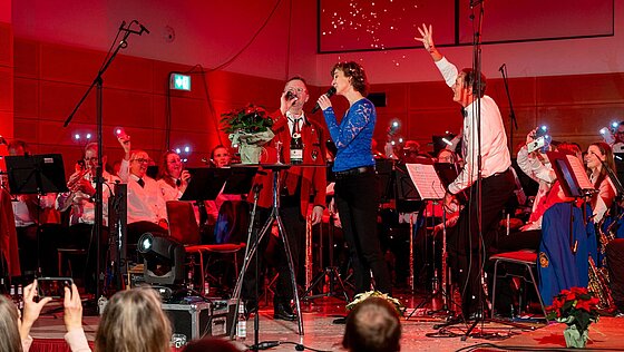 Konzert mit Dirigenten auf der Bühne am Mikrophon 